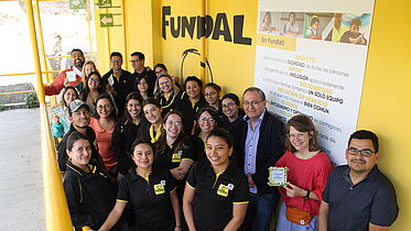 A group of people pose for a picture in front of a yellow wall.